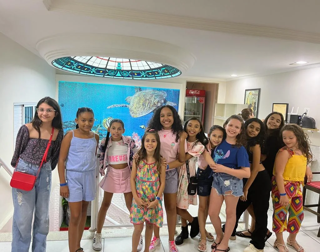 Grupo reunido no salão, com a claraboia e o painel de fundo