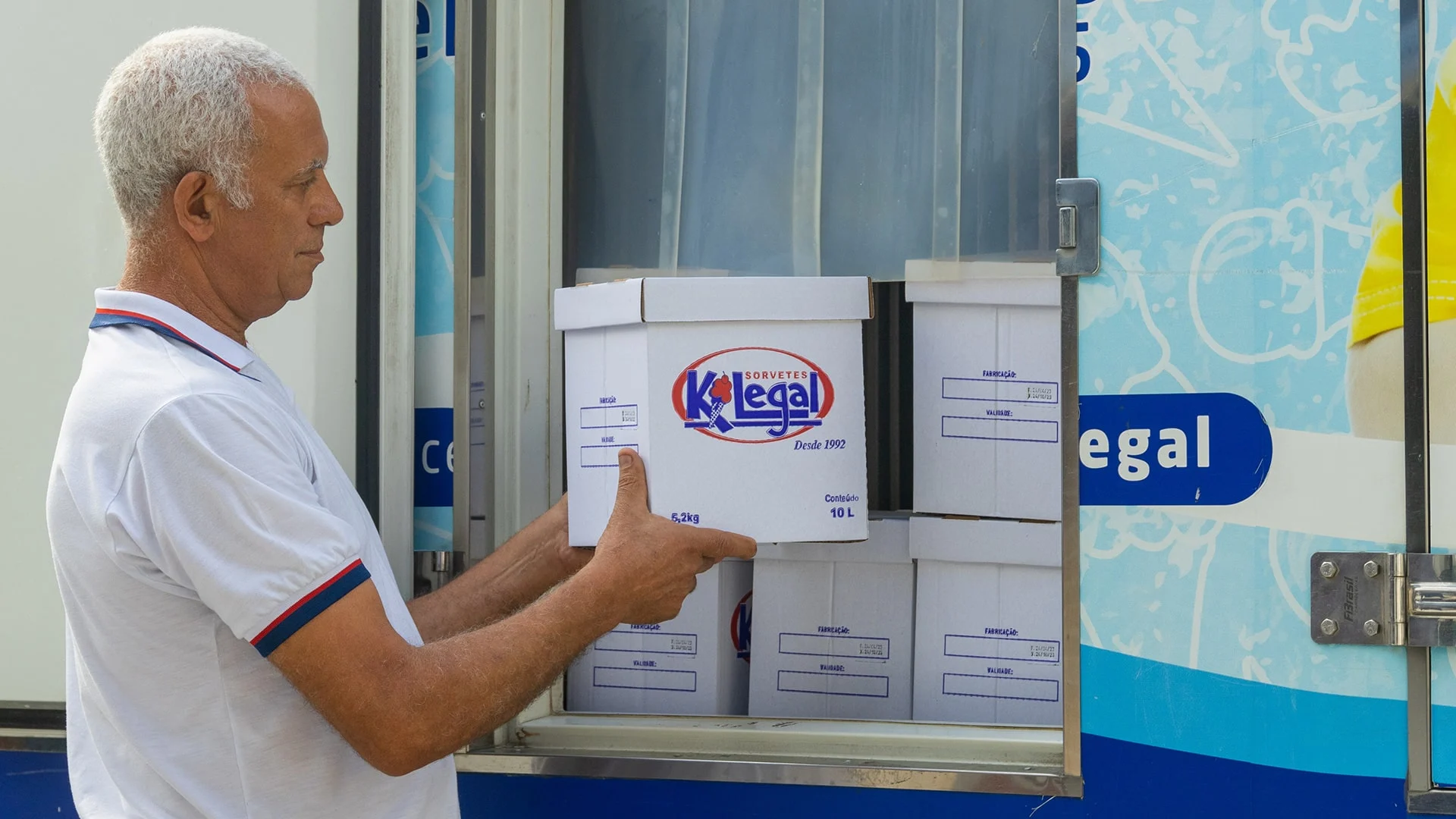 Entregador da KiLegal colocando caixas de sorvete de 10 litros no caminhão refrigerado